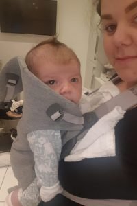 Jamie carrying her newborn in a grey Baby Bjorn carrier