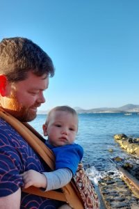 Dad beside the sea front carrying with a colourful Ergo