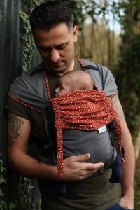 Man carrying a baby in a red and grey Mamaruga Zensling