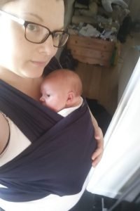 Kimmy cuddling her newborn in a black Moby wrap