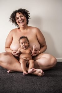 Amy's home waterbirth. Picture of Amy, naked, sat crosslegged on a carpet with 6 month old Winnie in her lap.