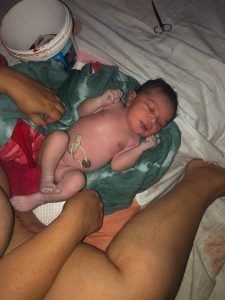 Baby Winnie, out of the pool on a towel, cord tied, with the placenta in a bucket nearby. Amy's home waterbirth