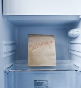 image shows a freezer with nothing in it except a paper bag with 'delivery' written on it - Egg freezing in the UK with a high BMI